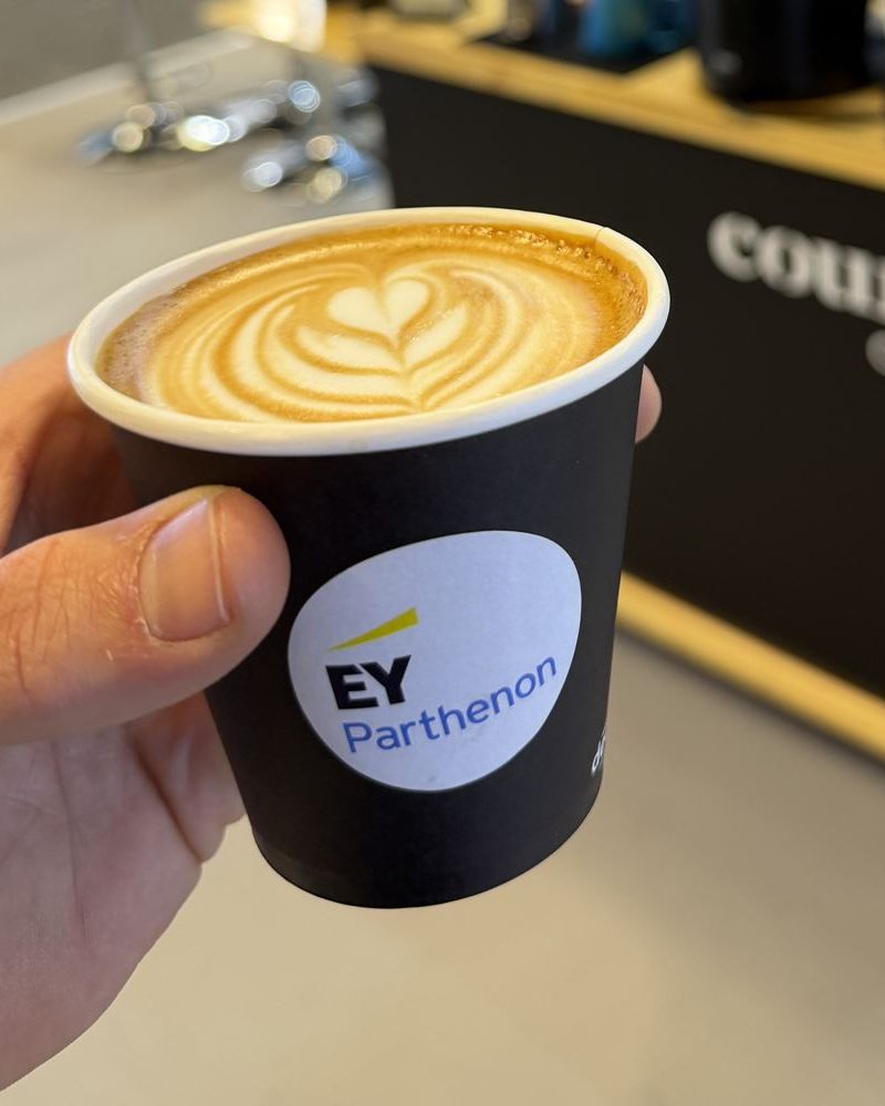 Close up of a latte in a cup carrying an EY Parthenon sticker
