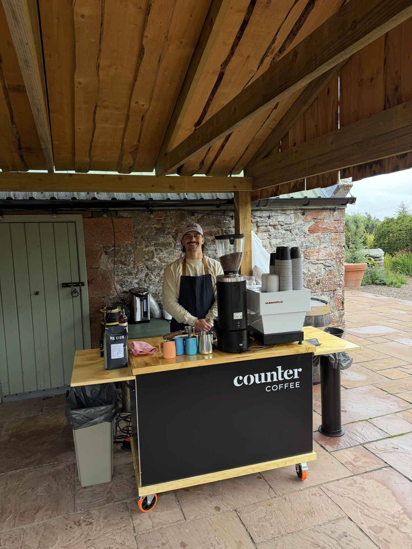 Damien serving from the cart under a timber barn roof