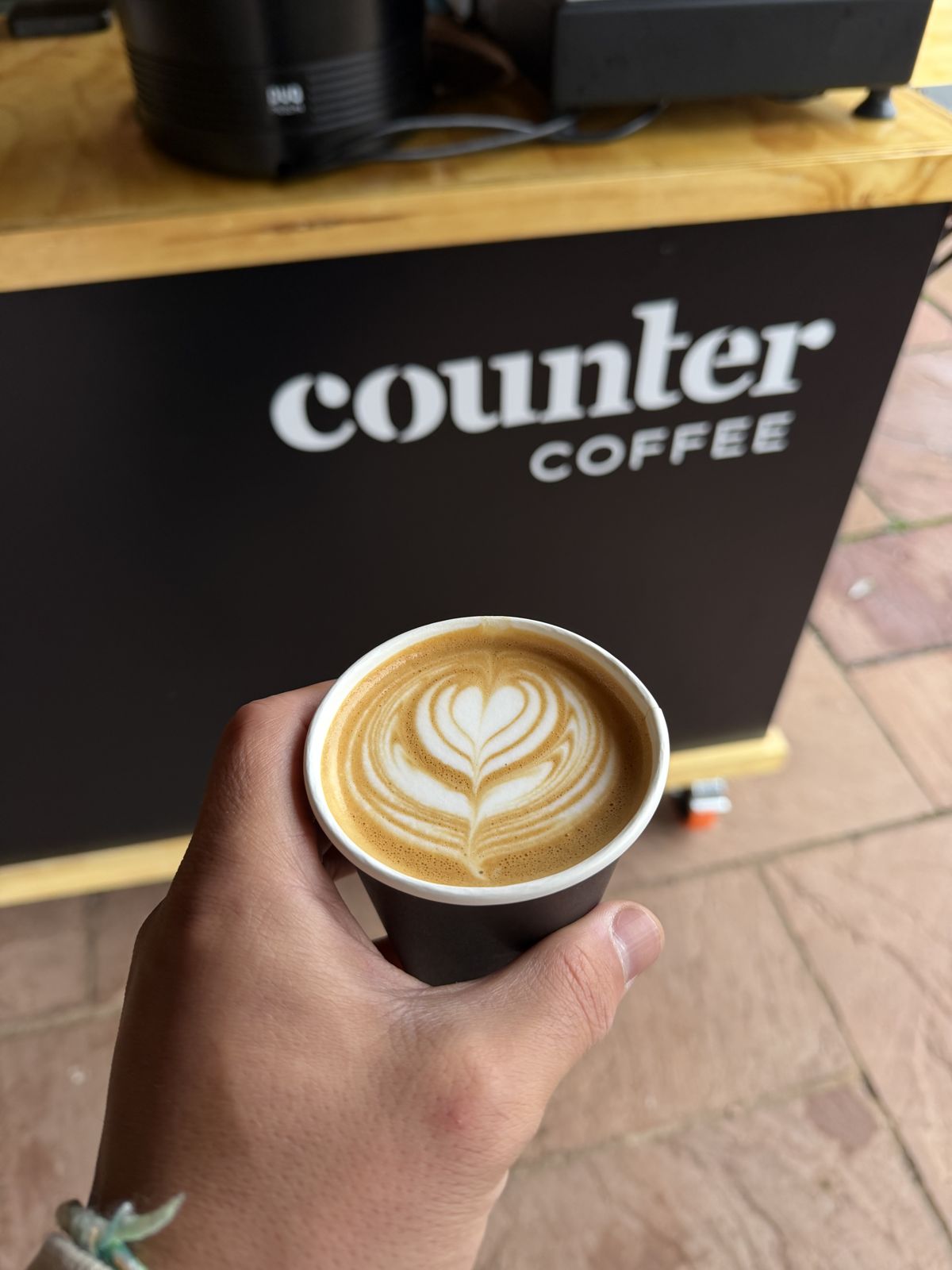 A latte held up in front of the cart at an outdoor event